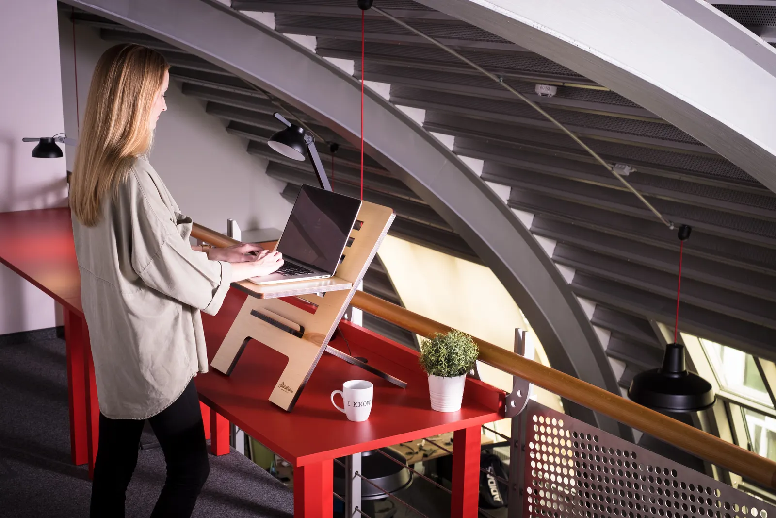 Woman using a laptop on a standing desk indoors in a creative workspace