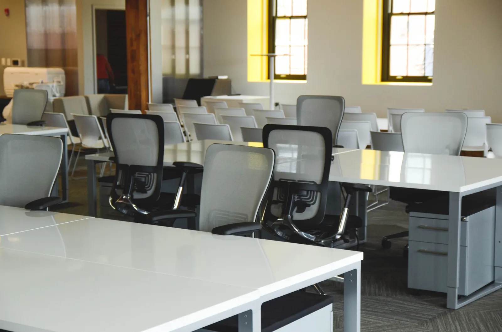 Spacious open office workspace with desks, chairs, and natural lighting