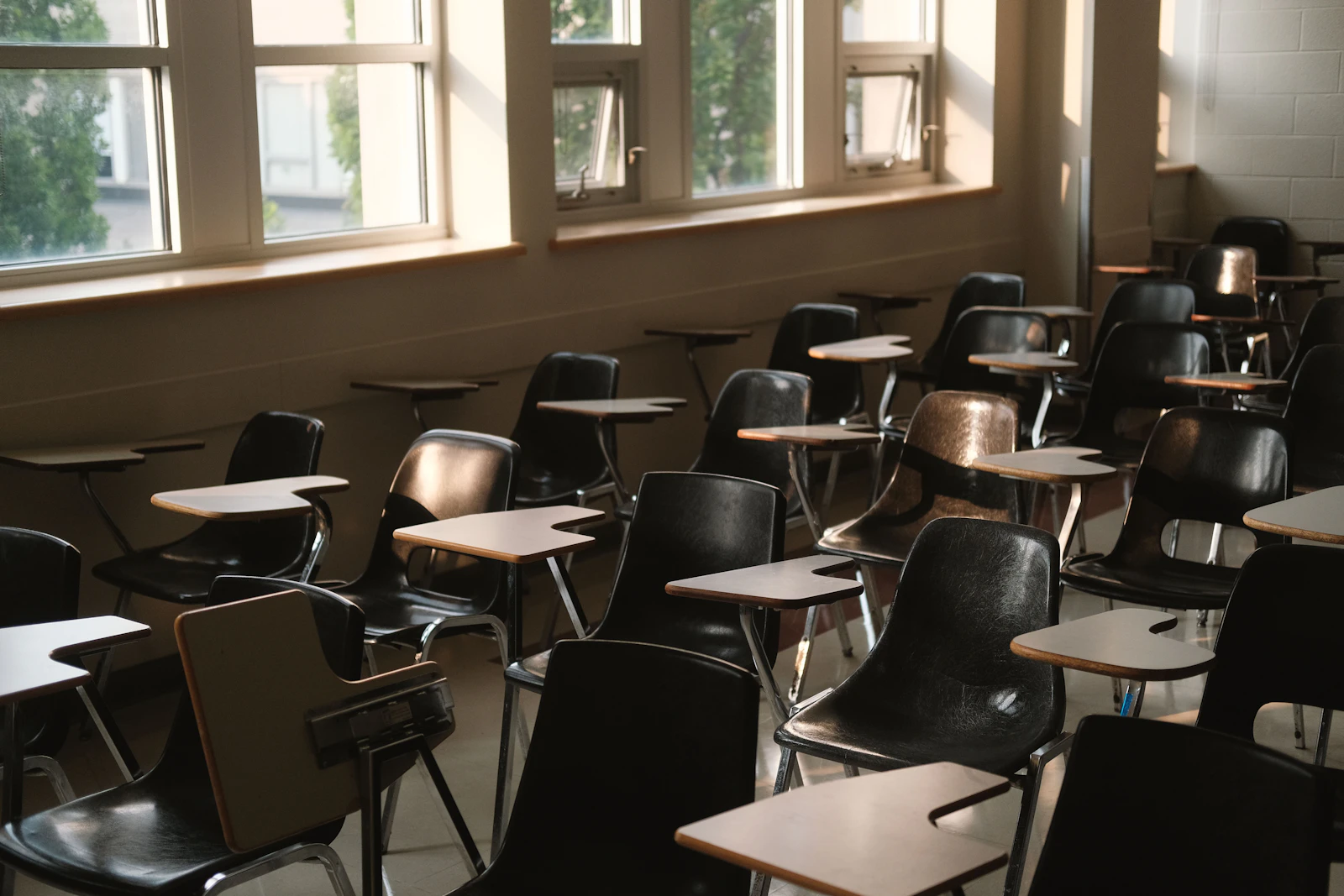 Empty classroom with desks and chairs by windows