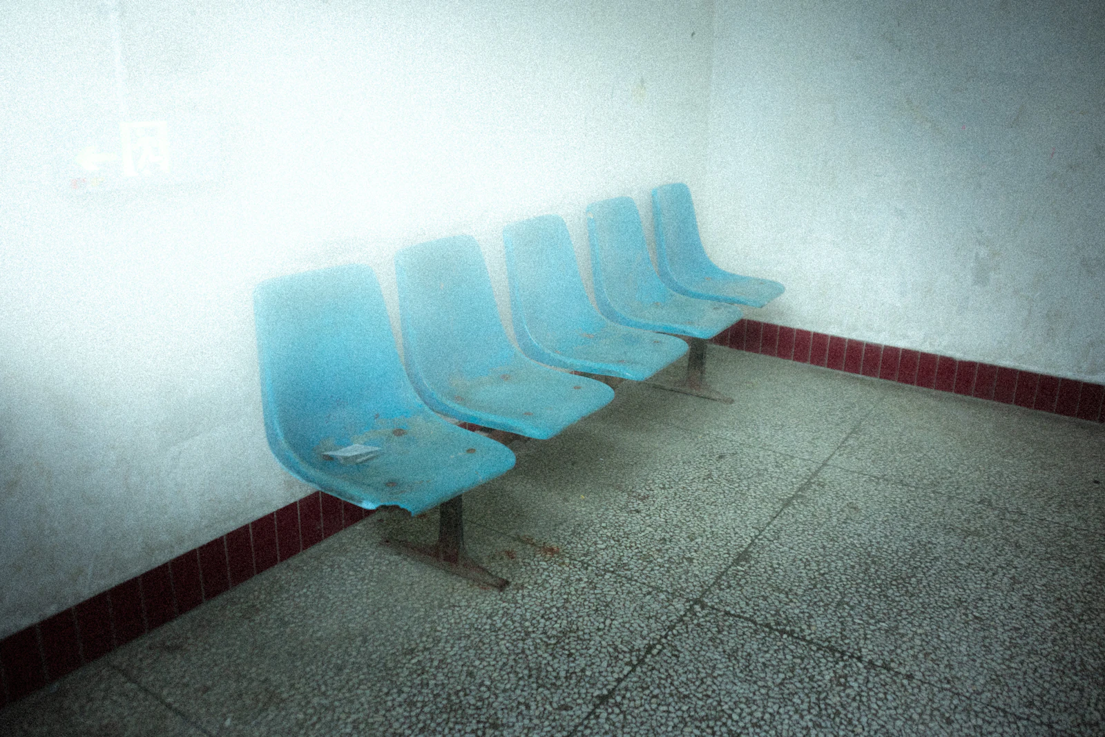 Row of empty blue plastic chairs in a waiting room